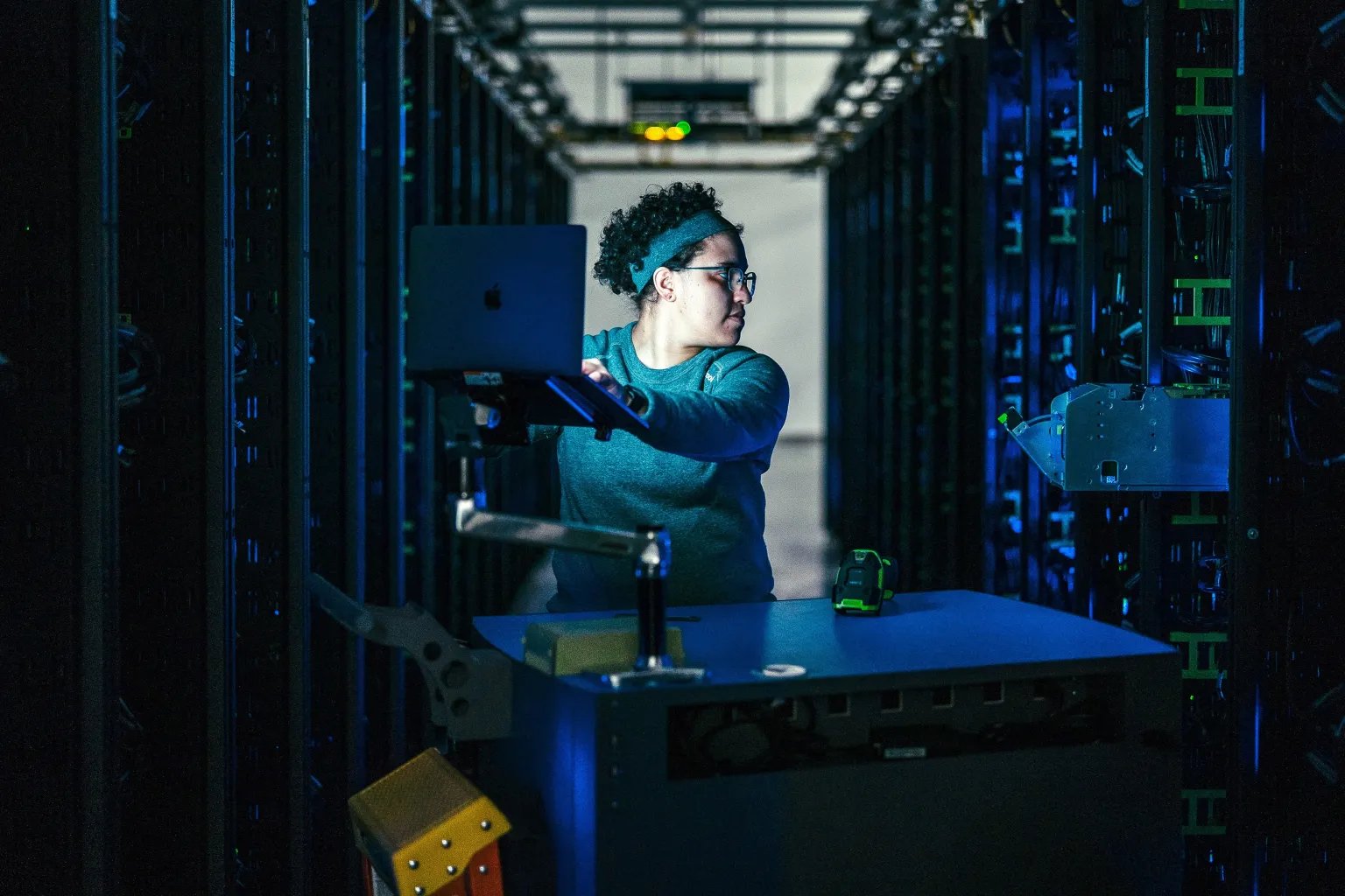Data center repair technician working between server racks